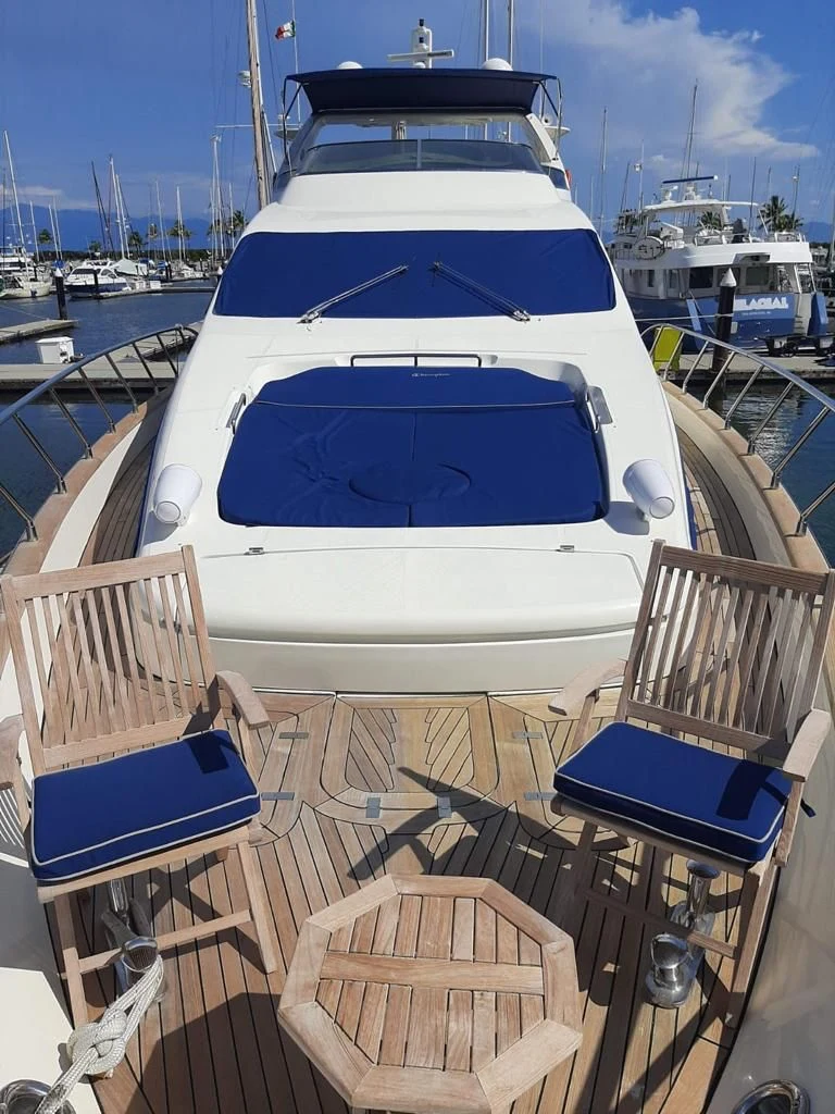 Yacht foredeck with teak chairs and blue sun cushions